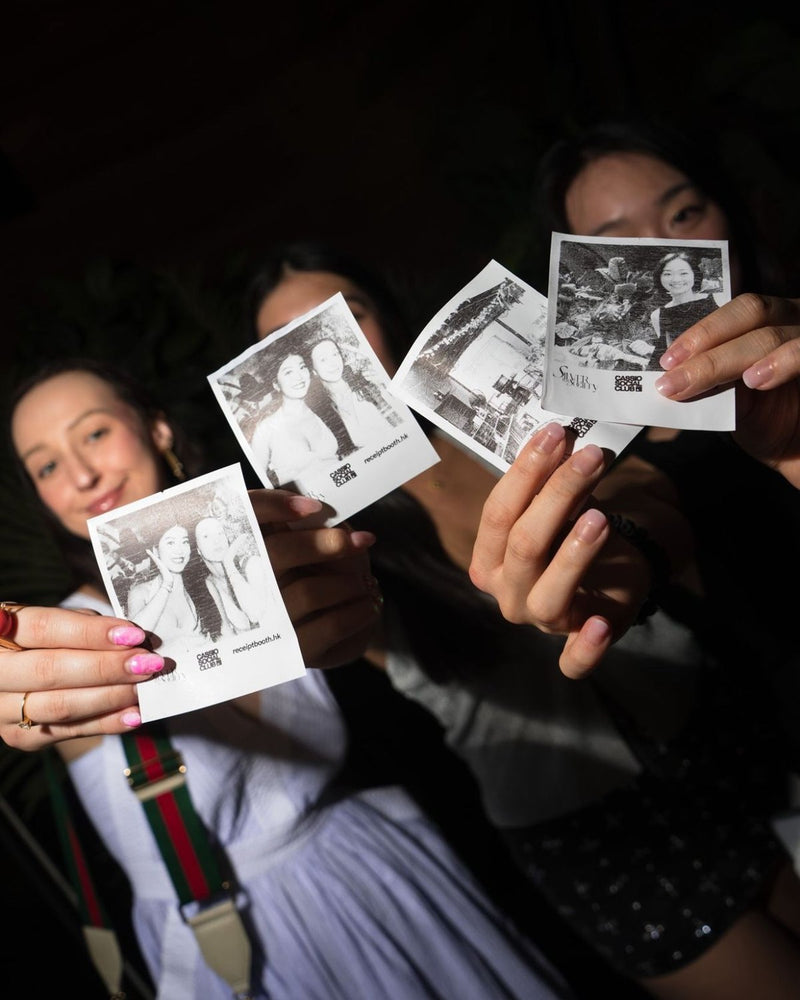 Three guests holding up black and white printed photos