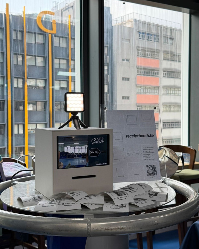 Receipt Booth on a high round table by a window, with printed receipts spread around it