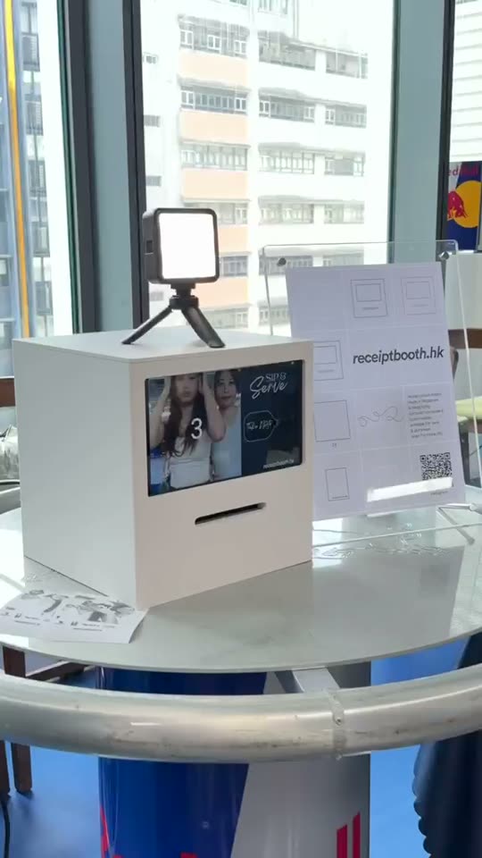 Cream Receipt Booth with a small light on top, on a high round table by a window, counting down on its screen
